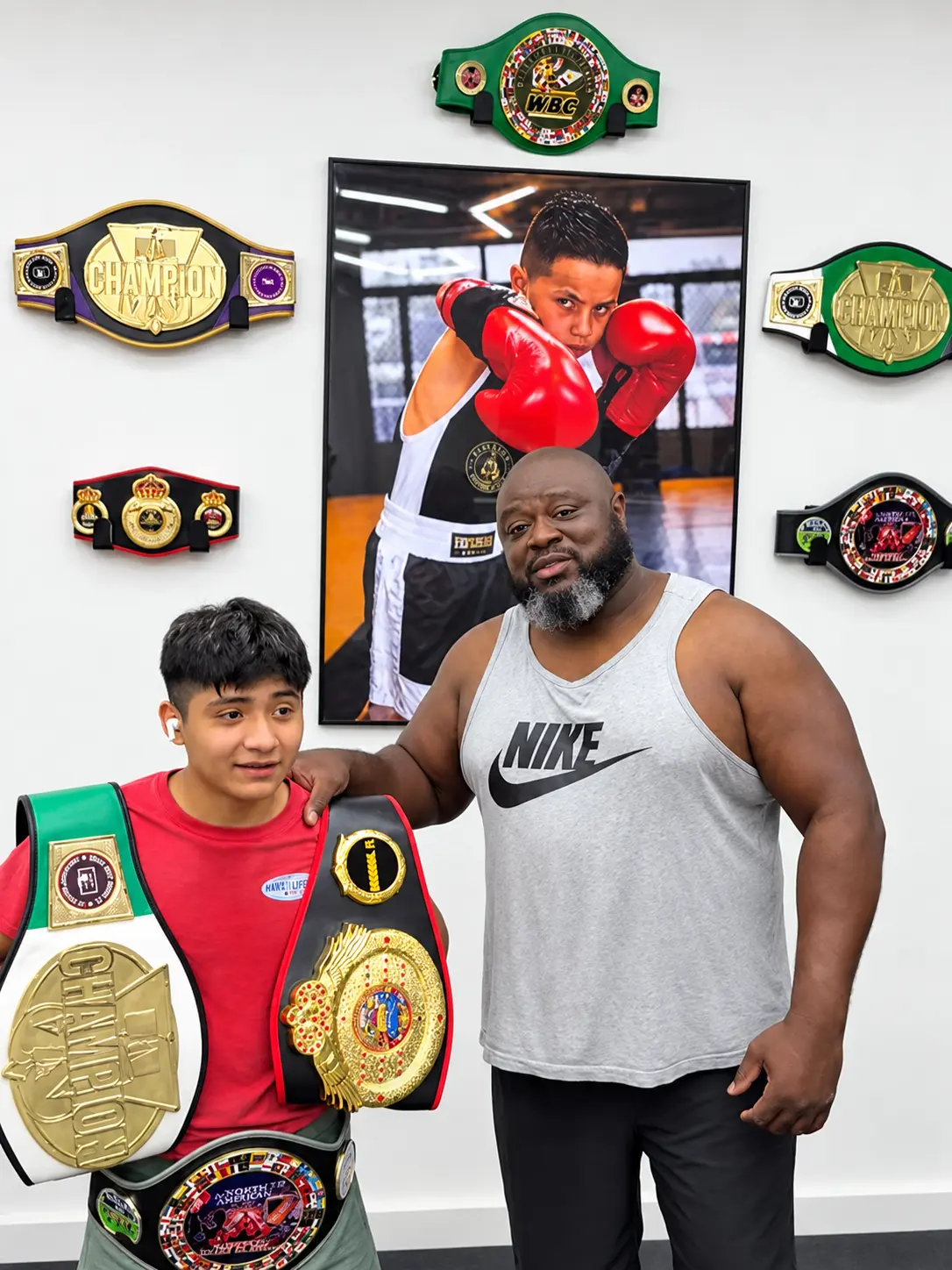 Vencedor coach and young champion in front of the championship belt wall